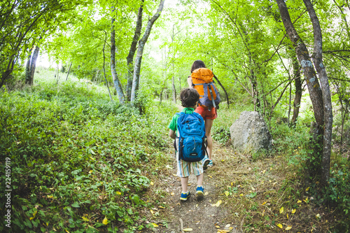 A woman and her child walk along a forest trail.