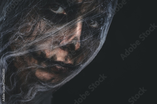 Creepy character covered with spiderweb on black background