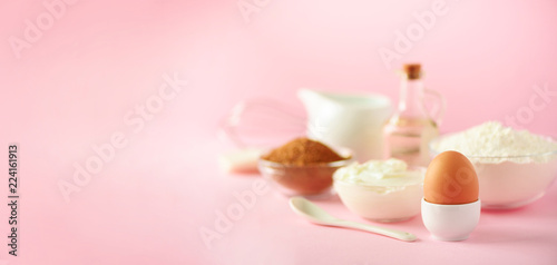 Banner with copy space. Bakery food frame, cooking concept. Different baking ingredients - butter, sugar, flour, milk, eggs, oil, spoon, rolling pin, brush, whisk over pink background.