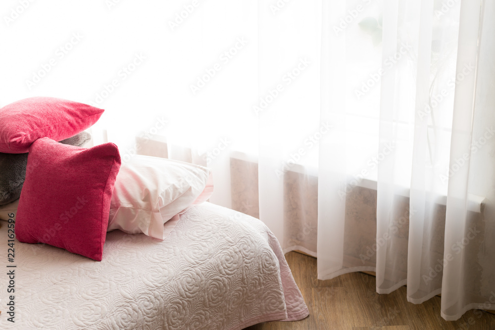 the interior of the bedroom. bedroom with a large bed. bed with pillows. bedside table with flowers. the walls are of brick. large window in the room