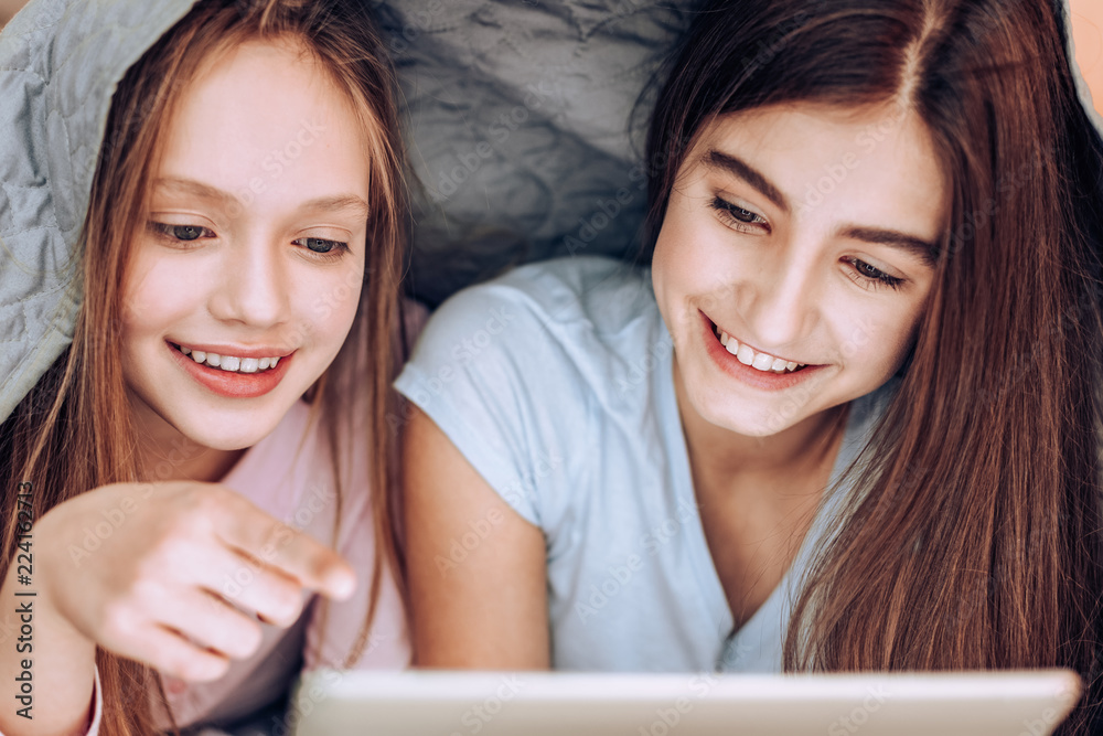 Happy together. Cheerful brunette keeping smile on face while staring at her gadget Happy together. Cheerful brunette keeping smile on face while staring at her gadget