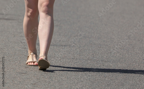 Legs of a girl walking along the road