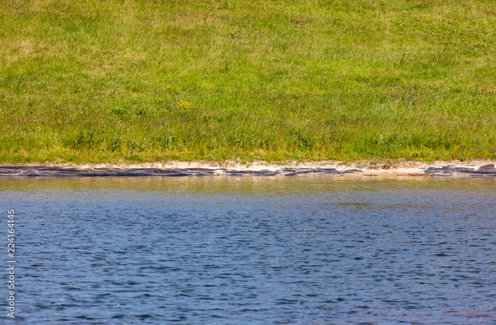 The shore of a pond with a lawn The shore of a pond with a lawn