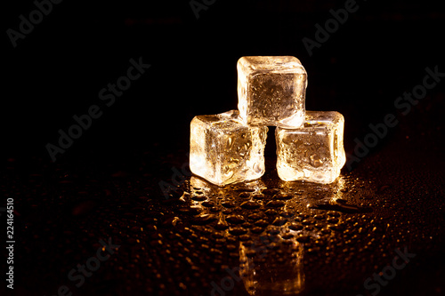 Golden ice cubes on black background. © peterkai