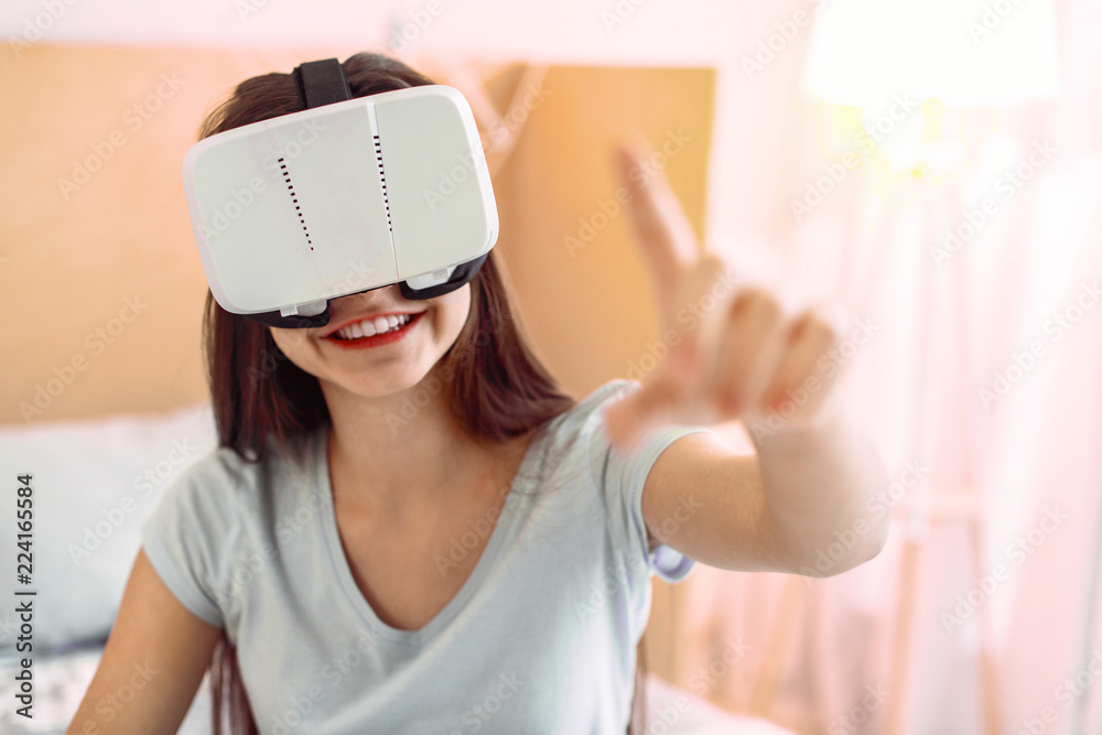 VR gadget. Amazing brunette keeping smile on her face while looking forward at her hand VR gadget. Amazing brunette keeping smile on her face while looking forward at her hand