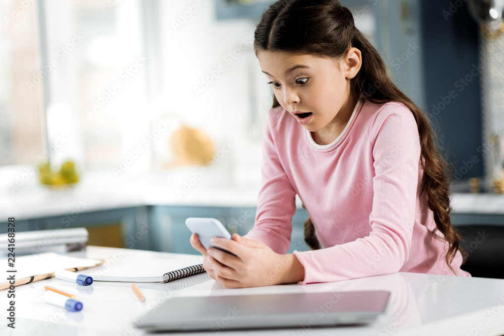 Digital era. Sincere astonished girl holding phone and opening mouth Digital era. Sincere astonished girl holding phone and opening mouth