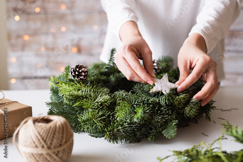 Fotografie Hands of unrecognizable woman decorating christmas wreath.