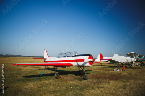 Fototapeta Naklejka Na Ścianę i Meble -  A small white with red plane stands on grass