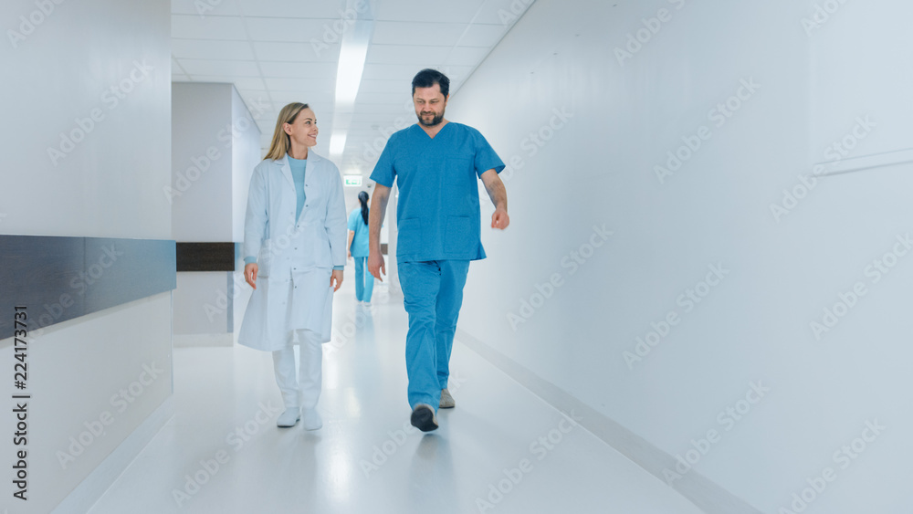 Surgeon and Female Doctor Walk Through Hospital Hallway in a Hurry while Talking about Patient's Health. Modern Bright Hospital with Professional Staff.
