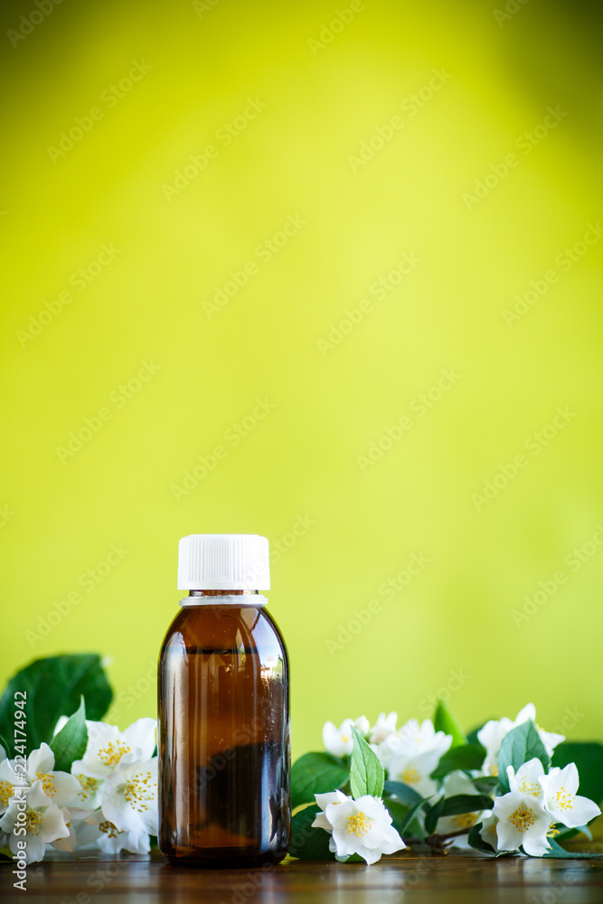 Essential aroma oil with jasmine on a green Essential aroma oil with jasmine on a green