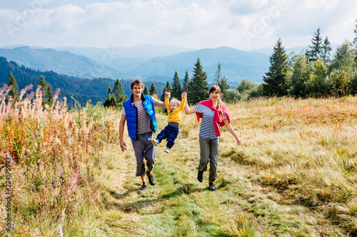 Active father and mother playing with their son on mountain in autumnr time. Young people having fun in landscape nature - Concept of travel, friendly family. Warm filter.