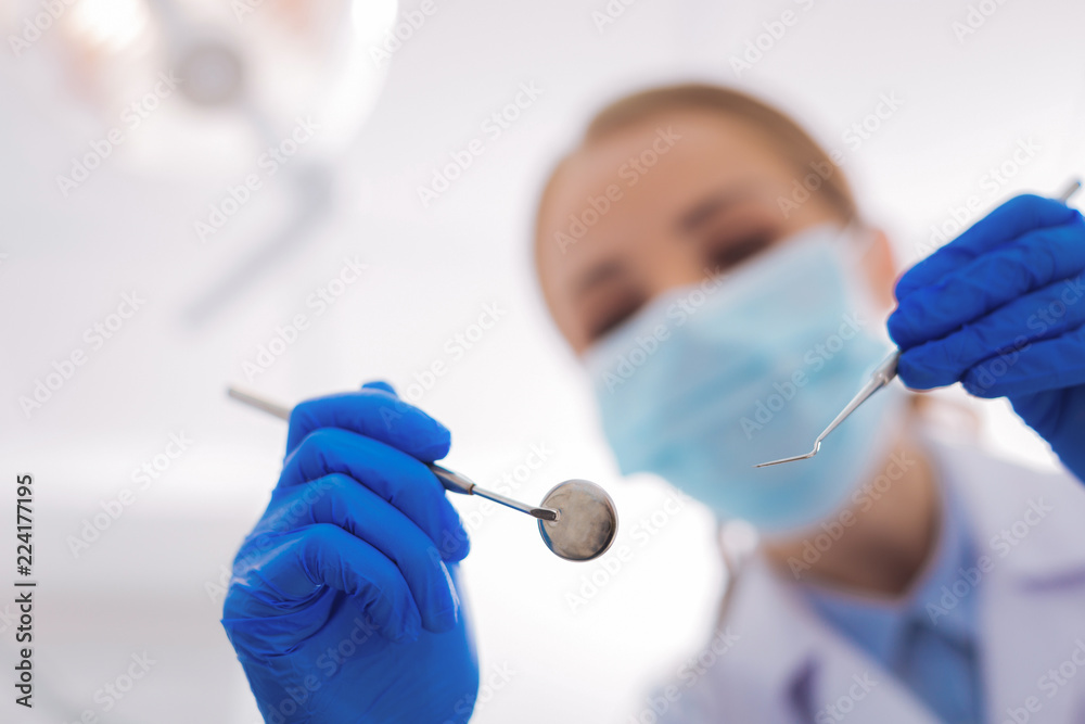 Important instruments. Clever professional dentist feeling confident while being in a modern personal dental clinic and holding necessary instruments Important instruments. Clever professional dentist feeling confident while being in a modern personal dental clinic and holding necessary instruments