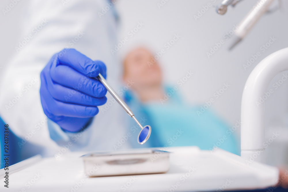 Taking dental mirror. Calm professional doctor taking a special dental mirror while examining the teeth of a new patient Taking dental mirror. Calm professional doctor taking a special dental mirror while examining the teeth of a new patient