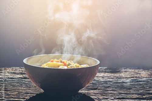 Soft focus Bowl of hot food with steam on dark background. photo