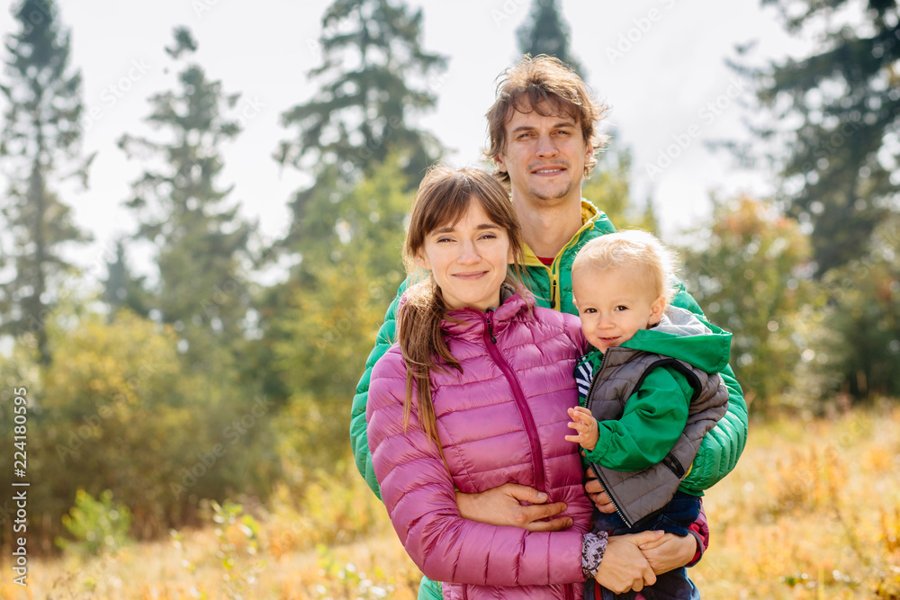 Portrait of happy family mother, father and toddler son wearing colorful duck jacket are traveling on Carpathain mountains. Traveling with children, tourism and people concept. Copy space. Portrait of happy family mother, father and toddler son wearing colorful duck jacket are traveling on Carpathain mountains. Traveling with children, tourism and people concept. Copy space.