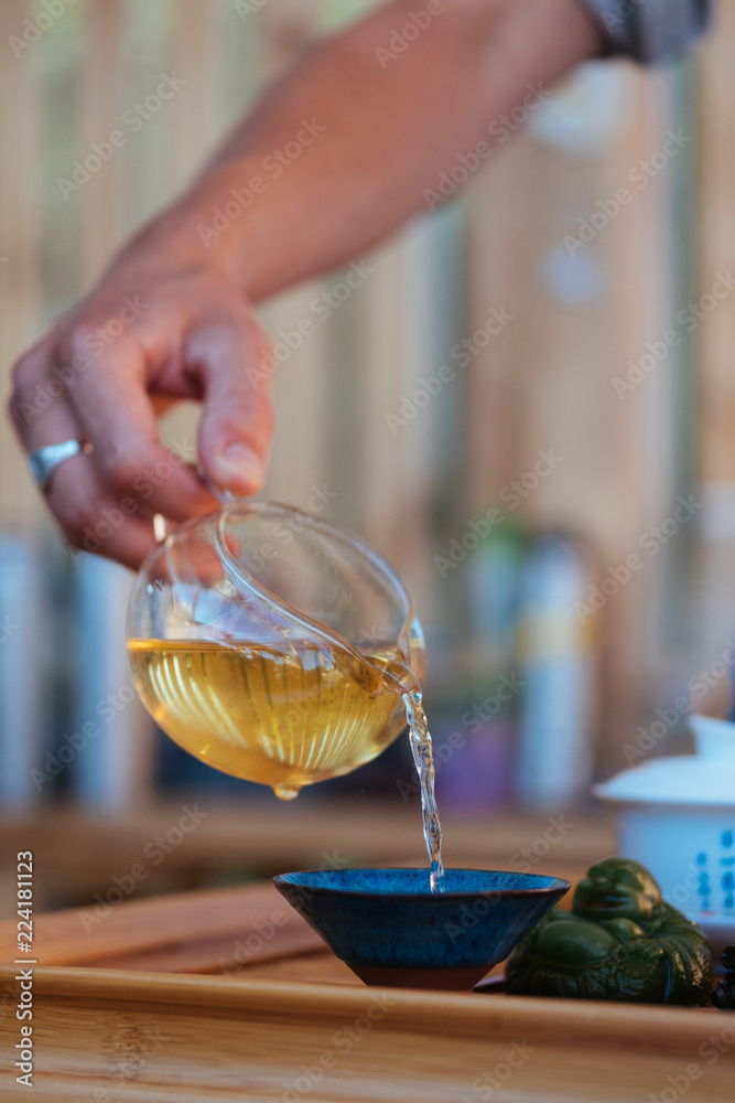 Tea ceremony. Master poured tea from a glass teapot into a cup Tea ceremony. Master poured tea from a glass teapot into a cup