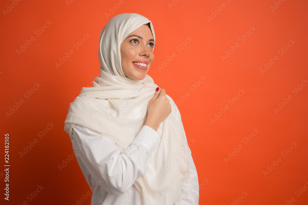 Happy arab woman in hijab. Portrait of smiling girl, posing at red studio background. Young emotional woman. The human emotions, facial expression concept. Front view.