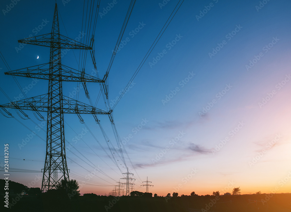 Fototapeta premium słupy elektryczne o zachodzie słońca transportujące czystą energię odnawialną