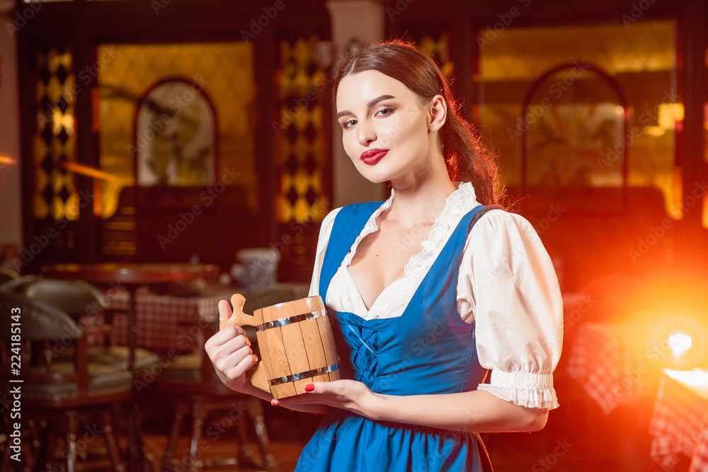 Young beautiful girl with a wooden mug of beer in hands at a party Oktoberfest. Young beautiful girl with a wooden mug of beer in hands at a party Oktoberfest.