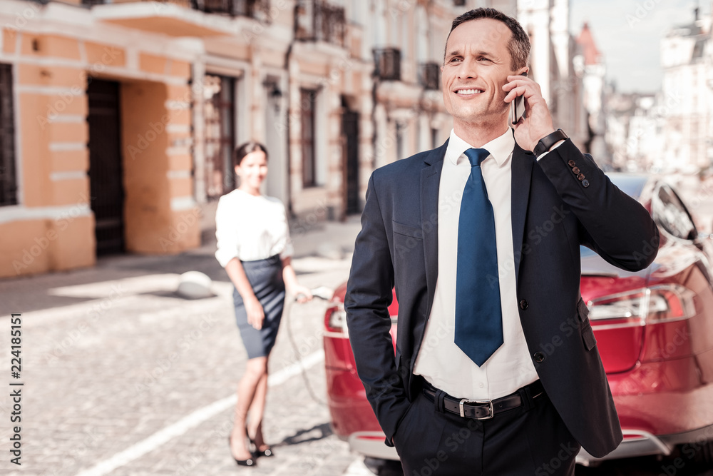 Collective work. Handsome man keeping smile on his face and putting right hand into pocket while looking aside Collective work. Handsome man keeping smile on his face and putting right hand into pocket while looking aside