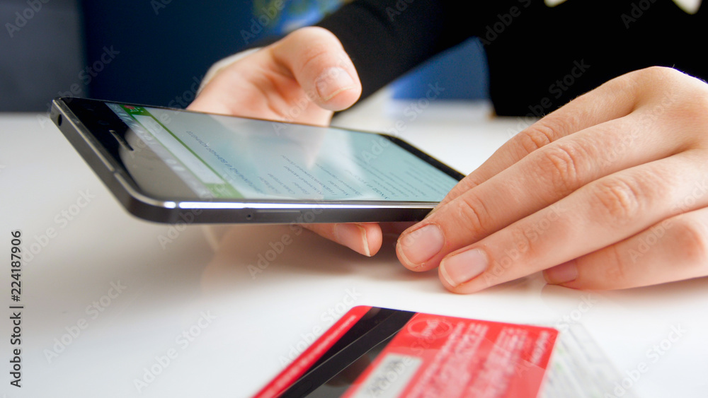 Closeup photo of woman browsing online shop on smartphone and paying with credit card Closeup photo of woman browsing online shop on smartphone and paying with credit card