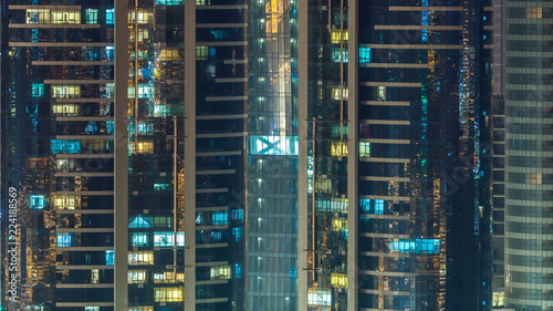Window of the multi-storey skyscrapers of glass and steel office lighting and people within timelapse