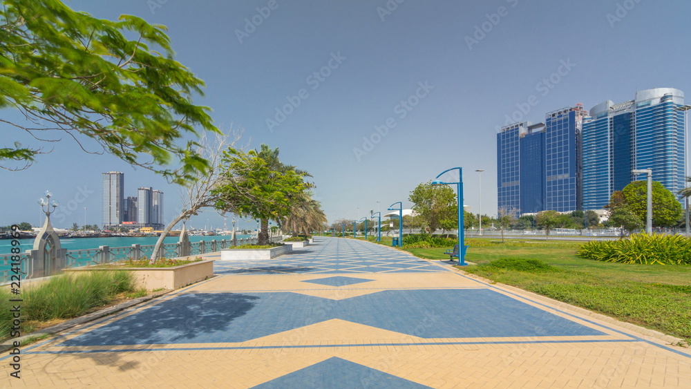 Obraz premium Corniche boulevard beach park along the coastline in Abu Dhabi timelapse hyperlapse with skyscrapers on background.