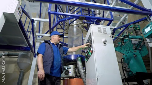 Worker checking and set up LDPE Plastic Blown film bag making machine inside cleanroom for industrial export.