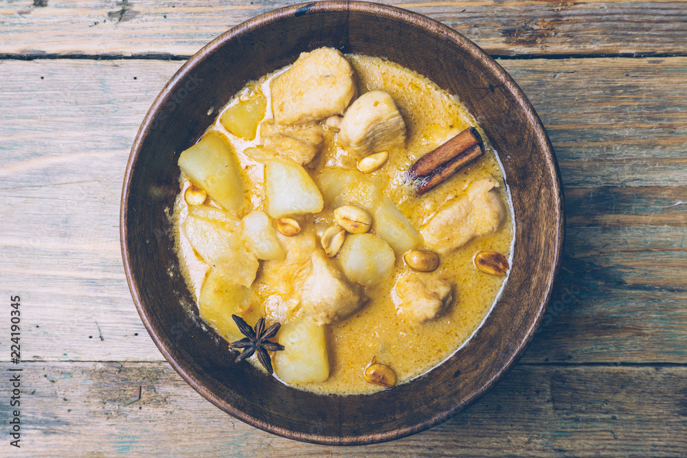 Massaman curry (chicken curry) whith cinnamon sticks and plane riсe on wooden background. Coconut milk curry.