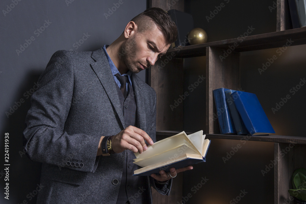 Elegant man in business suit with book. Portrait of handsome stylish man in library. Lawyer reads the book Elegant man in business suit with book. Portrait of handsome stylish man in library. Lawyer reads the book