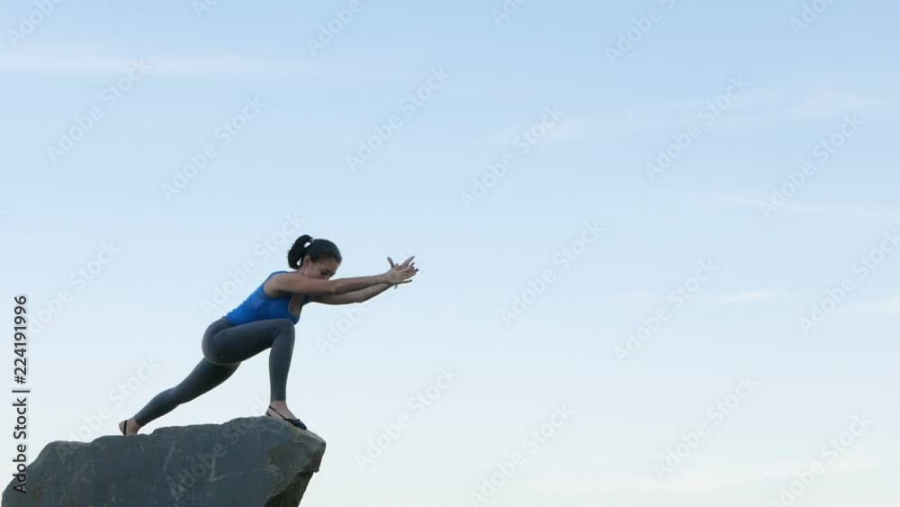 Happy young woman practicing yoga on the river rocks at sunset. Healthy active lifestyle concept. Slow Motion Happy young woman practicing yoga on the river rocks at sunset. Healthy active lifestyle concept. Slow Motion