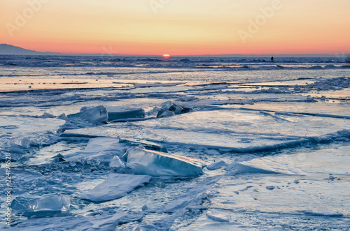 Walking in winter on the ice and snow texture. Sunset and silhouettes of people