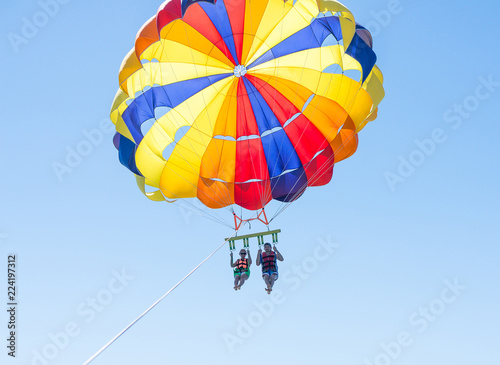 Happy couple Parasailing in Dominicana beach in summer. Couple under parachute hanging mid air. Having fun. Tropical Paradise. Positive human emotions, feelings, family, children, travel, vacation. 