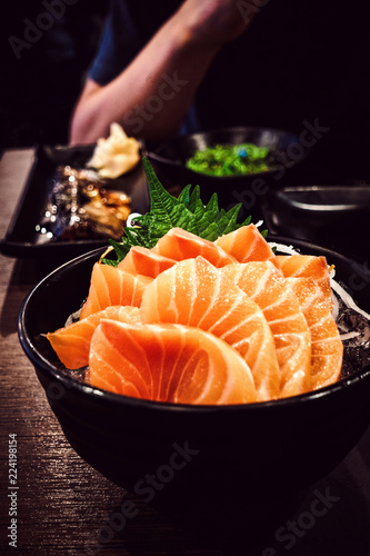 Sashimi salmon on the table in the restaurant light and dark.