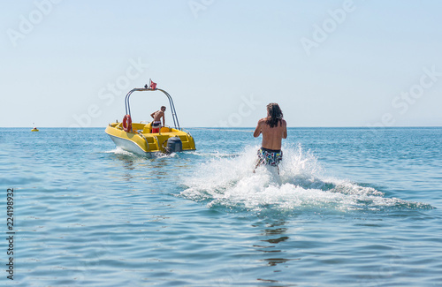 Young man glides on water skiing on the waves on the sea, ocean. Healthy lifestyle. Positive human emotions, feelings, joy. Funny cute boy making vacations and enjoying summer.