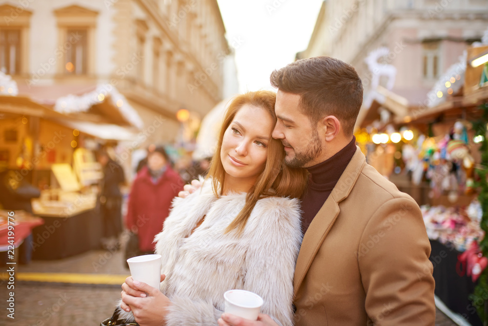 A beautiful young couple drinking mulled wine in a christmas market. A beautiful young couple drinking mulled wine in a christmas market.