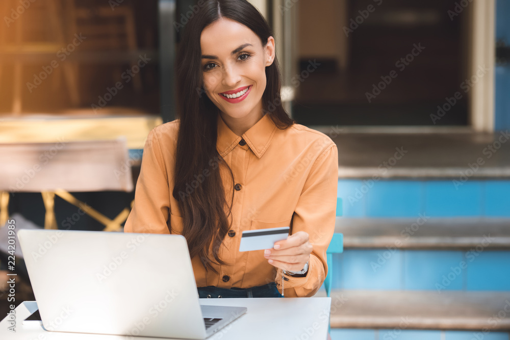 attractive stylish woman with credit card doing online shopping on laptop at table in cafe at city street attractive stylish woman with credit card doing online shopping on laptop at table in cafe at city street