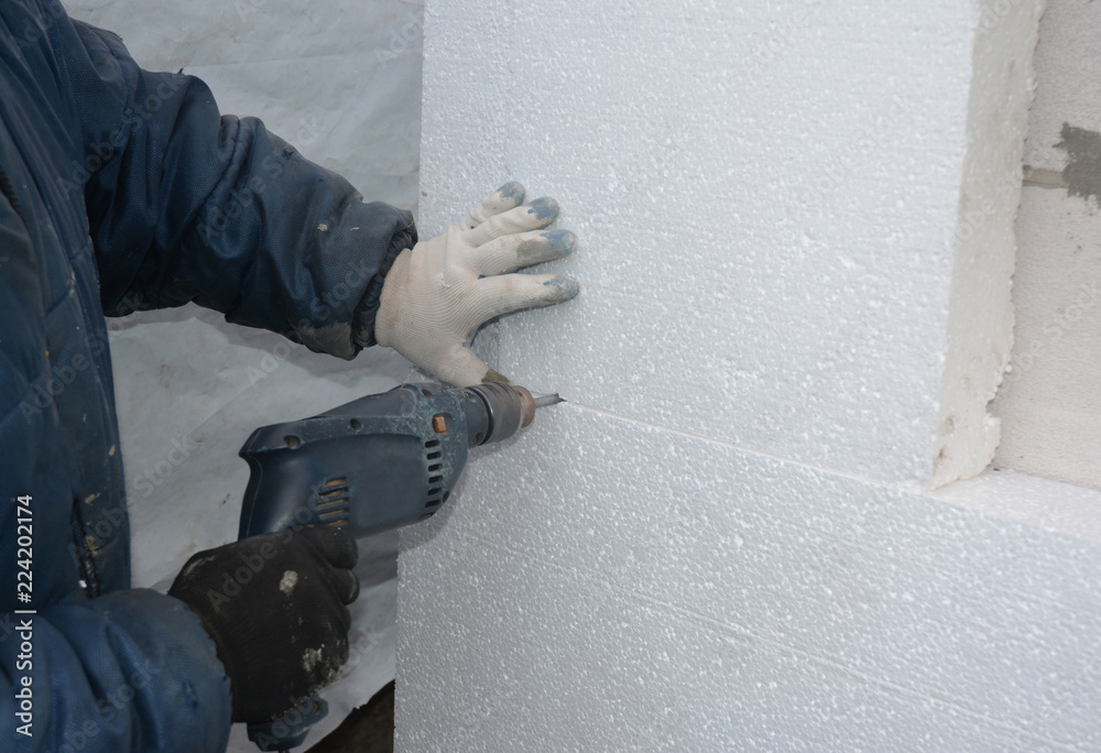 Wall Insulation. Builder drilling wall for installing anchors to hold