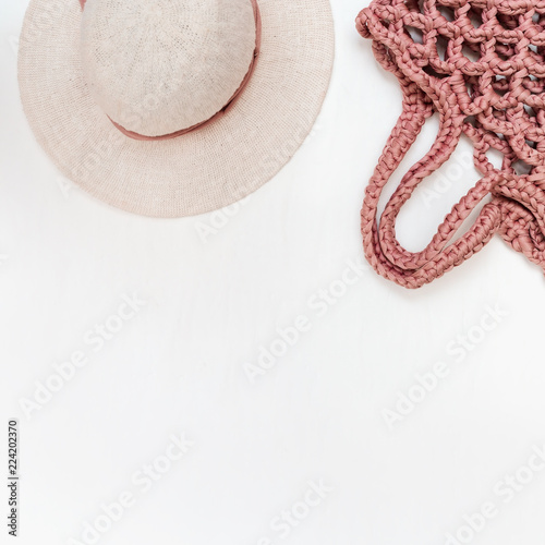 Travel tourism objects, hat for woman and stylish bag on light table. Vacation concept. Flat lay. Copy space.