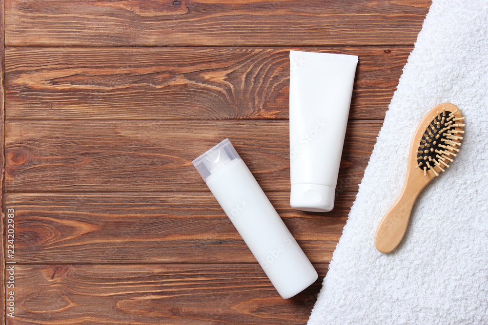 Obraz premium natural hair care products, hairbrush and towel on a wooden background top view. Shampoo, mask, balm. flatlay