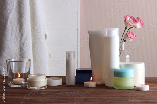 a set of usurious cosmetics, a towel and a candle on a wooden background. Skin care. photo