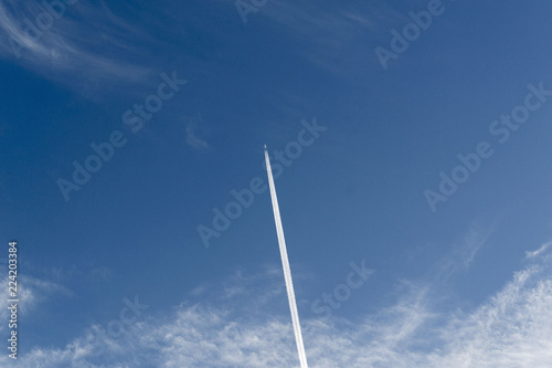 White trace of a flying plane in the blue sky