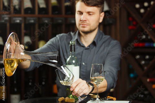 Sommelier pours white wine from decanter to the glass