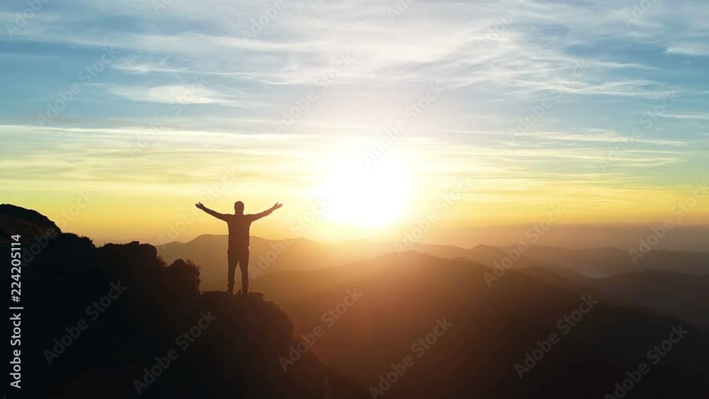 The man standing on the mountain and enjoying the sunrise