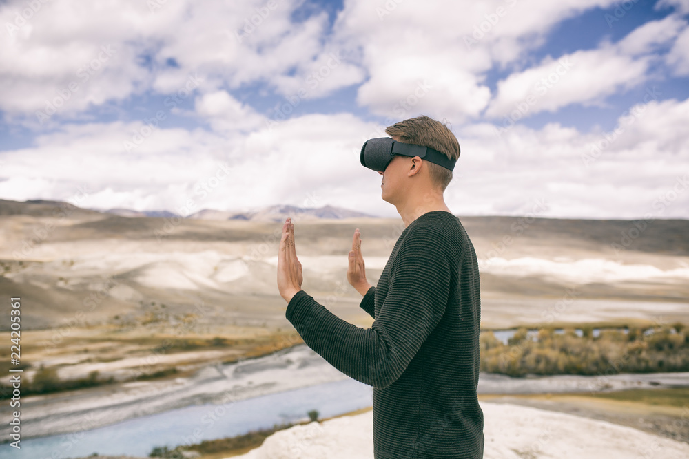 man in glasses of virtual reality stands on the background of nature