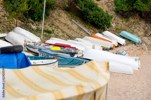 Several boats are parked by the beach. Covered with tarpaulins