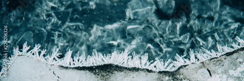 Ice fragments under thin layer of frozen river water. Dark blue natural background