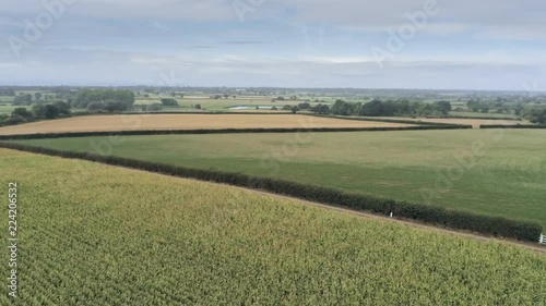Aerial view, rise up and panning move. Semi panorama of Cheshire plains and fields. Cloudy sky and haze hills in background