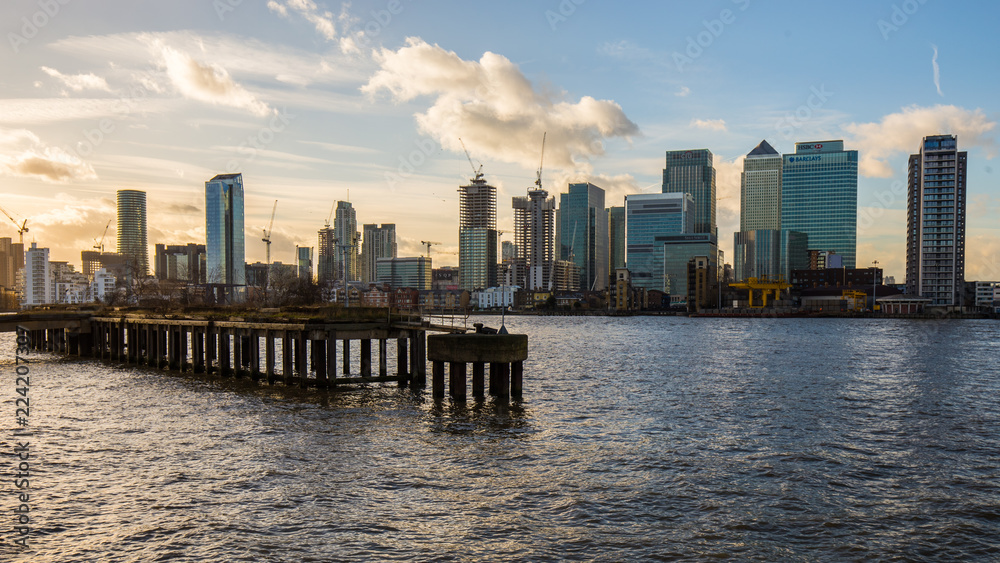 Modern skyscrapers of Canary Wharf with old overgrown pier and Thames in foreground, January 2018, Greenwich London