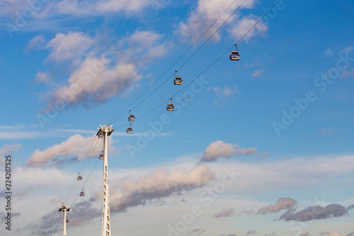 Emirates Air Line Cable Cars crossing the Thames with starting plane in the background, North Greenwich, London, January 2018